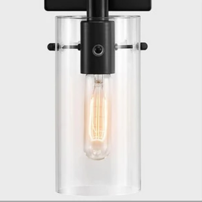 Set of 2 black wall sconces with hand-blown glass cylinder shades and bronze hardware, mountable up or down for modern or farmhouse interiors

