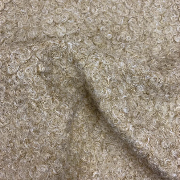 Tan king-size upholstered bed in bouclé fabric with wingback headboard and low-profile black metal legs.

