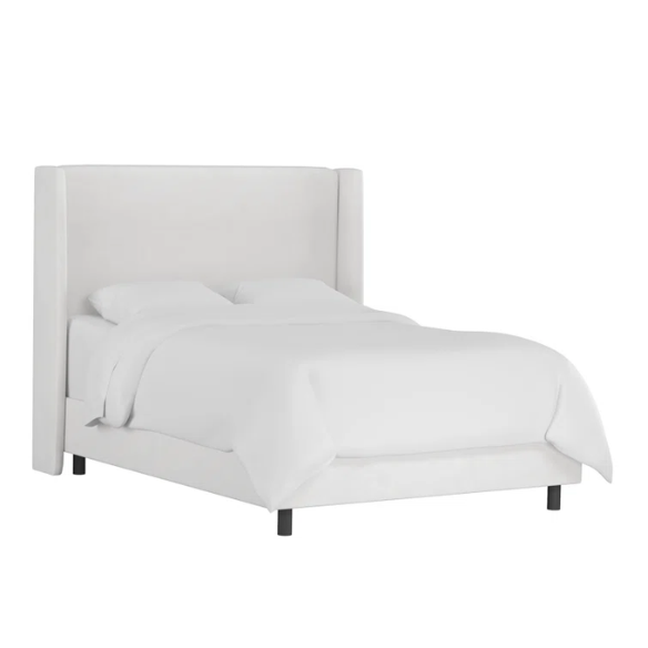 White king-size upholstered bed in velvet fabric with wingback headboard and low-profile black metal legs.

