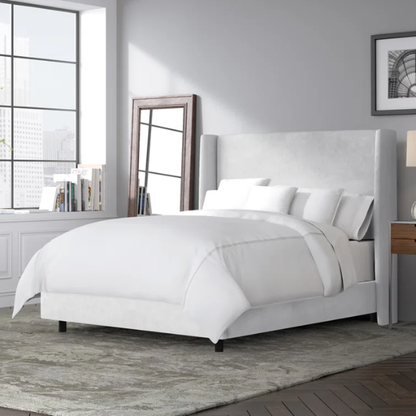 White king-size upholstered bed in velvet fabric with wingback headboard and low-profile black metal legs.

