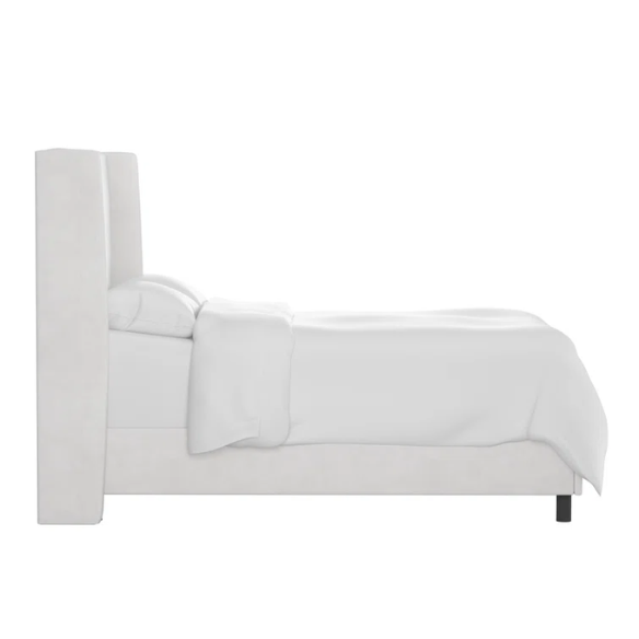 White king-size upholstered bed in velvet fabric with wingback headboard and low-profile black metal legs.

