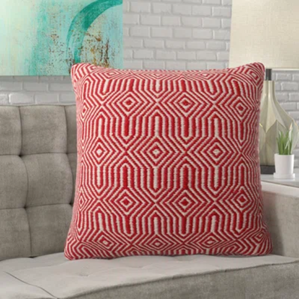 Red and cream geometric throw pillow on modern outdoor furniture with vibrant decor

