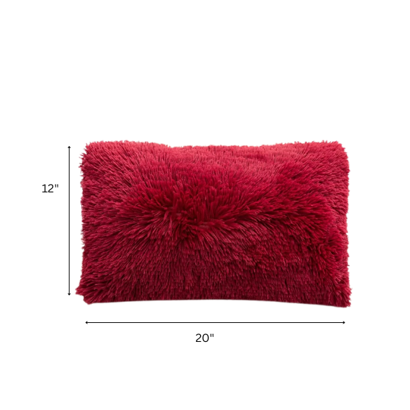 Set of two red wine faux fur throw pillows with plush shaggy texture on a modern velvet sofa

