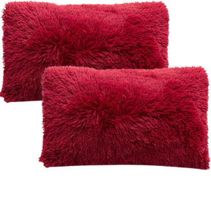 Set of two red wine faux fur throw pillows with plush shaggy texture on a modern velvet sofa

