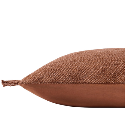 Rust cotton blend throw pillow with fringe, 22x22 square decorative cushion styled on a neutral-toned sofa for cozy, modern home décor.

