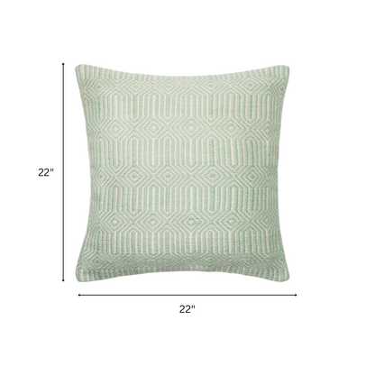 Seafoam green and cream geometric throw pillow on an outdoor patio chair with modern decor

