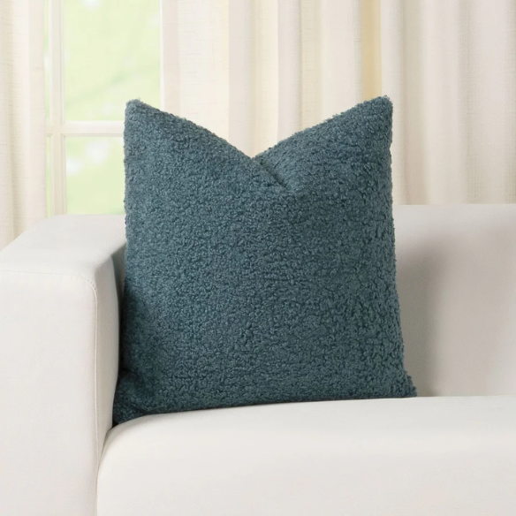 Turquoise bouclé throw pillow with textured loop fabric, square accent pillow on a modern sofa

