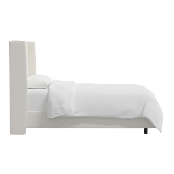 White linen upholstered king size bed with foam-padded wingback headboard, black low-profile metal legs, and sturdy wood frame.

