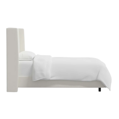 White linen upholstered king size bed with foam-padded wingback headboard, black low-profile metal legs, and sturdy wood frame.

