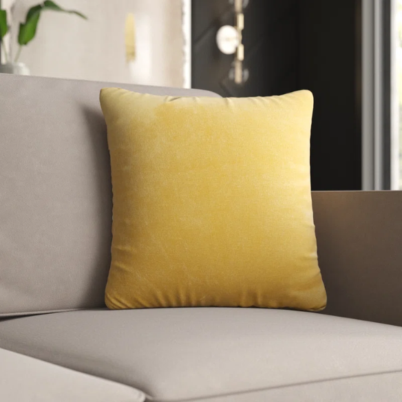 Yellow crushed velvet throw pillow, 16x16 square design with soft, reversible fabric and hidden zipper, styled on a light-toned sofa for a cheerful, cozy look.

