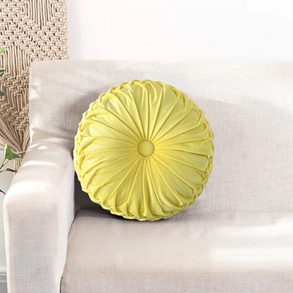 Yellow velvet round throw pillows with pleated detailing and button center, 14.5-inch set of two styled in a cozy, sunlit room.

